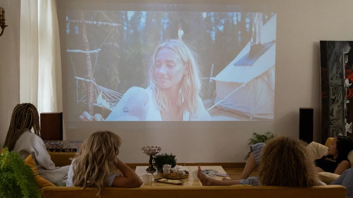Viewers on a sofa watching a movie projected onto a living-room wall; this is not LightBoks II output